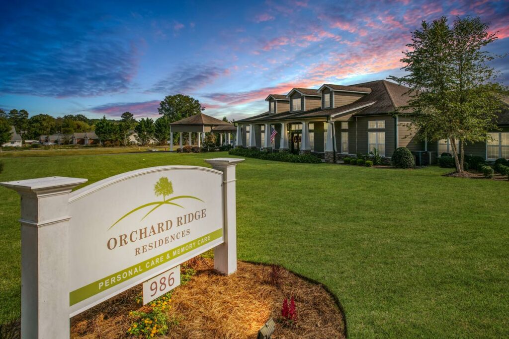 Orchard Ridge Residences' Personal Care and Memory Care sign in front of building exterior at sunset