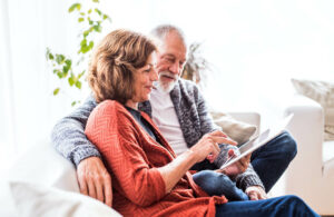 Orchard Ridge Residences | Senior couple relaxing on a couch looking at a tablet